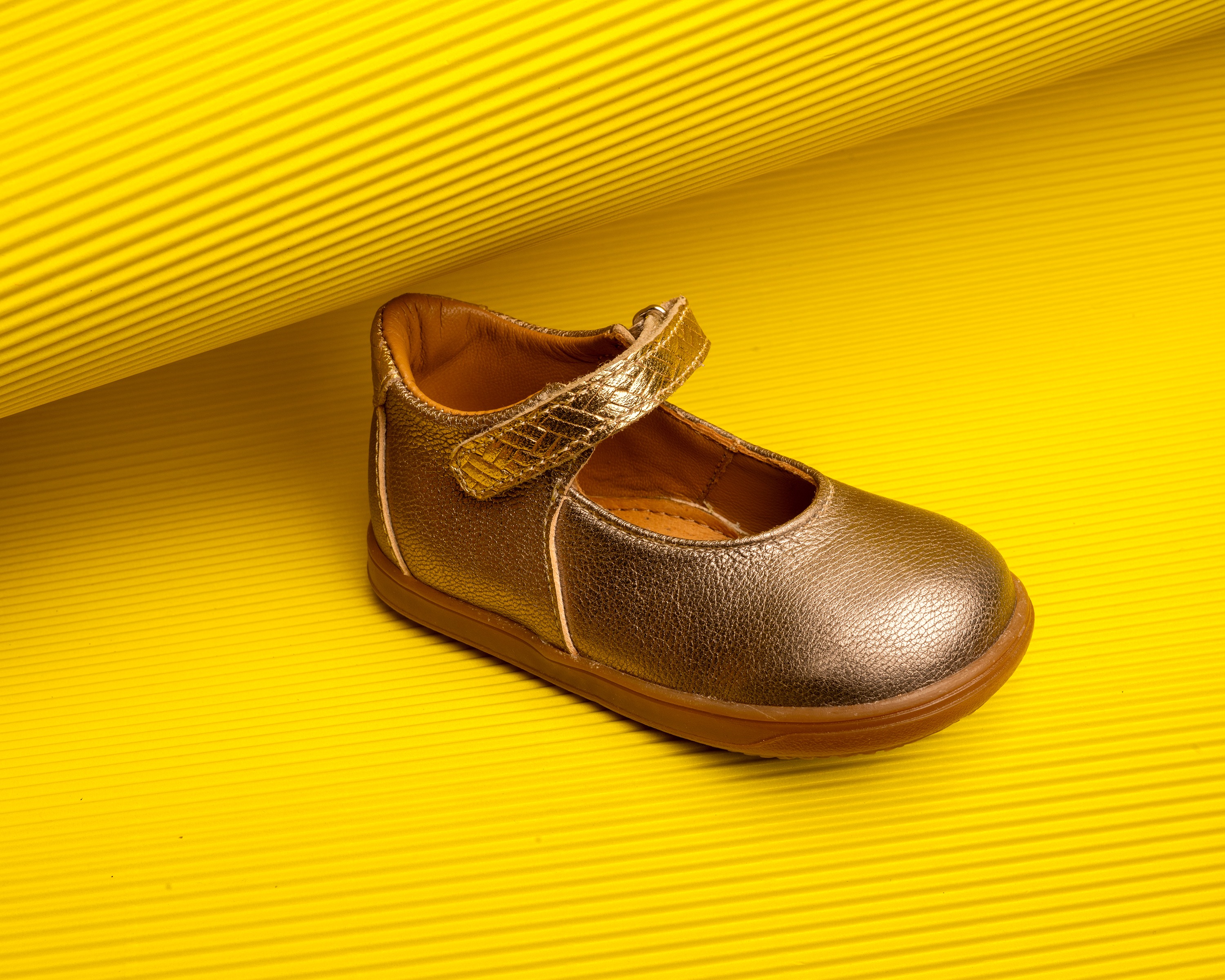 Ballerine dorée pour enfant sur fond jaune