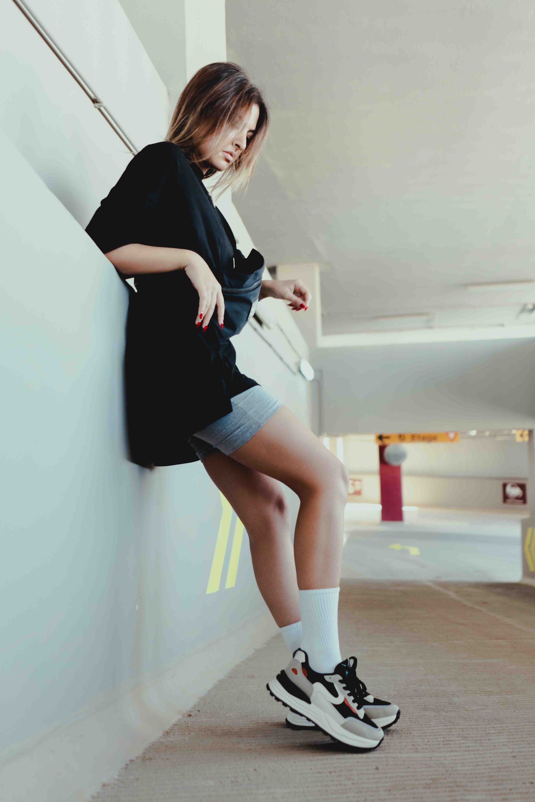 Femme en tenue streetwear et baskets dans un parking en béton