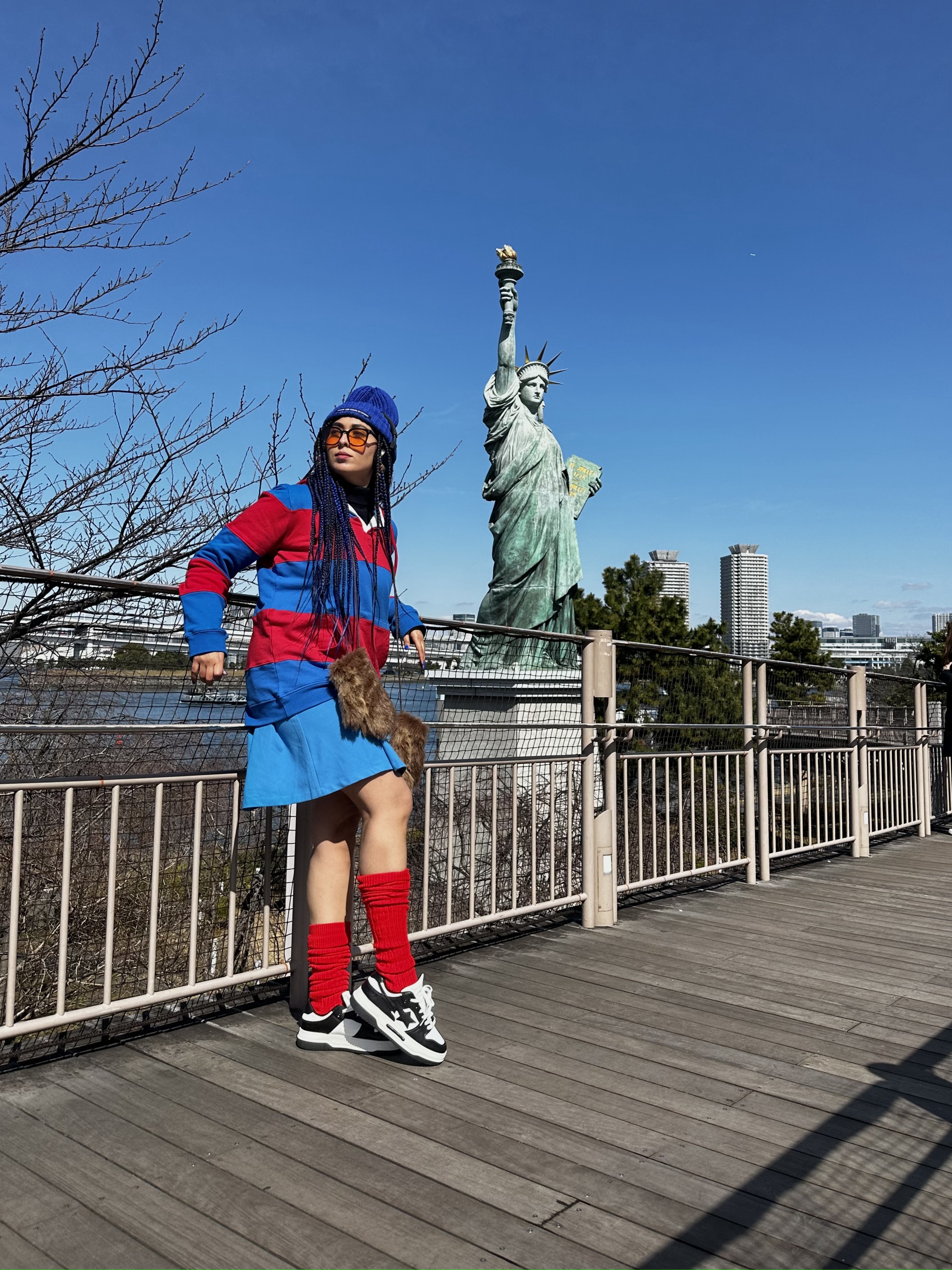 Femme en tenue streetwear devant une réplique de la statue de la Liberté